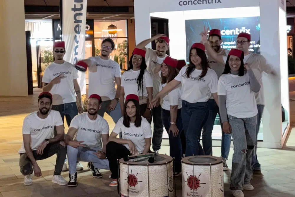 Team building groupe souriant en chemises blanches et chapeaux rouges.